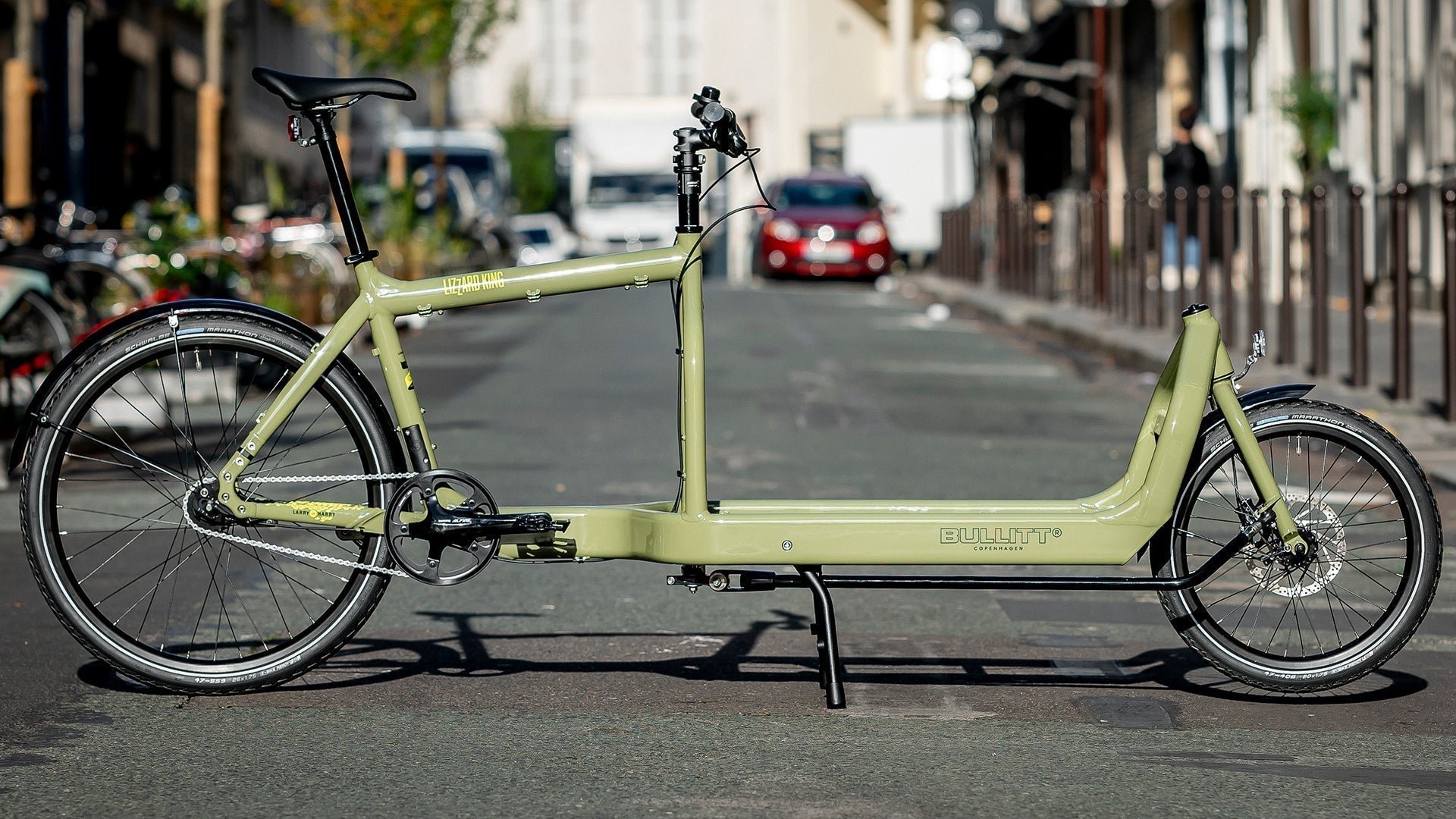 A light green Bullitt Cargo Bike parked in the street