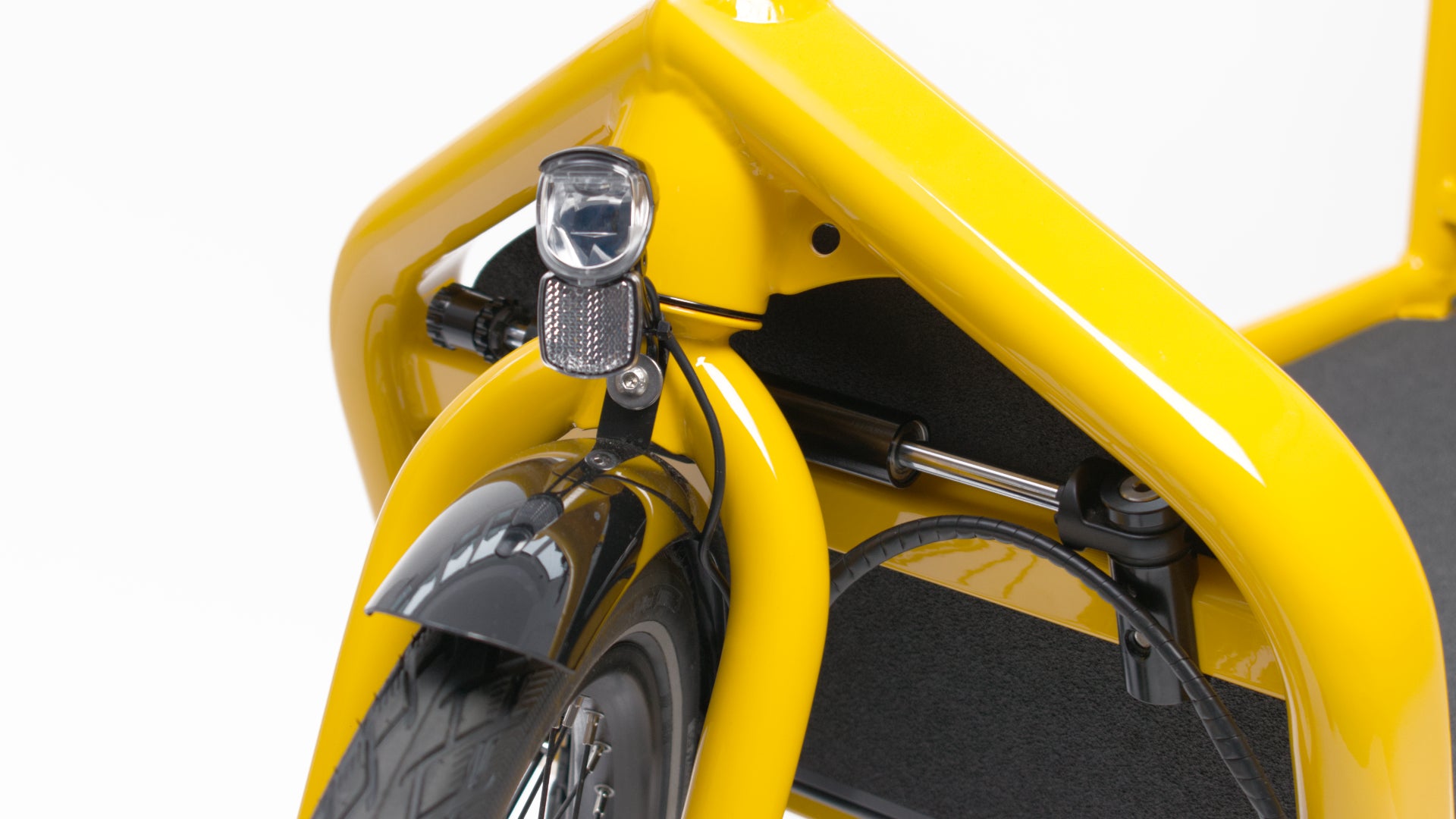 Closeup of a yellow Bullitt cargo bike front fork and headset, showing a hydraulic steering damper.
