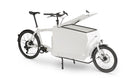A white eBullitt cargo bike with a lidded white aluminium cargo box mounted on the cargo bed. The lid is open, with a hydraulic arm and the locking mechanism visible.