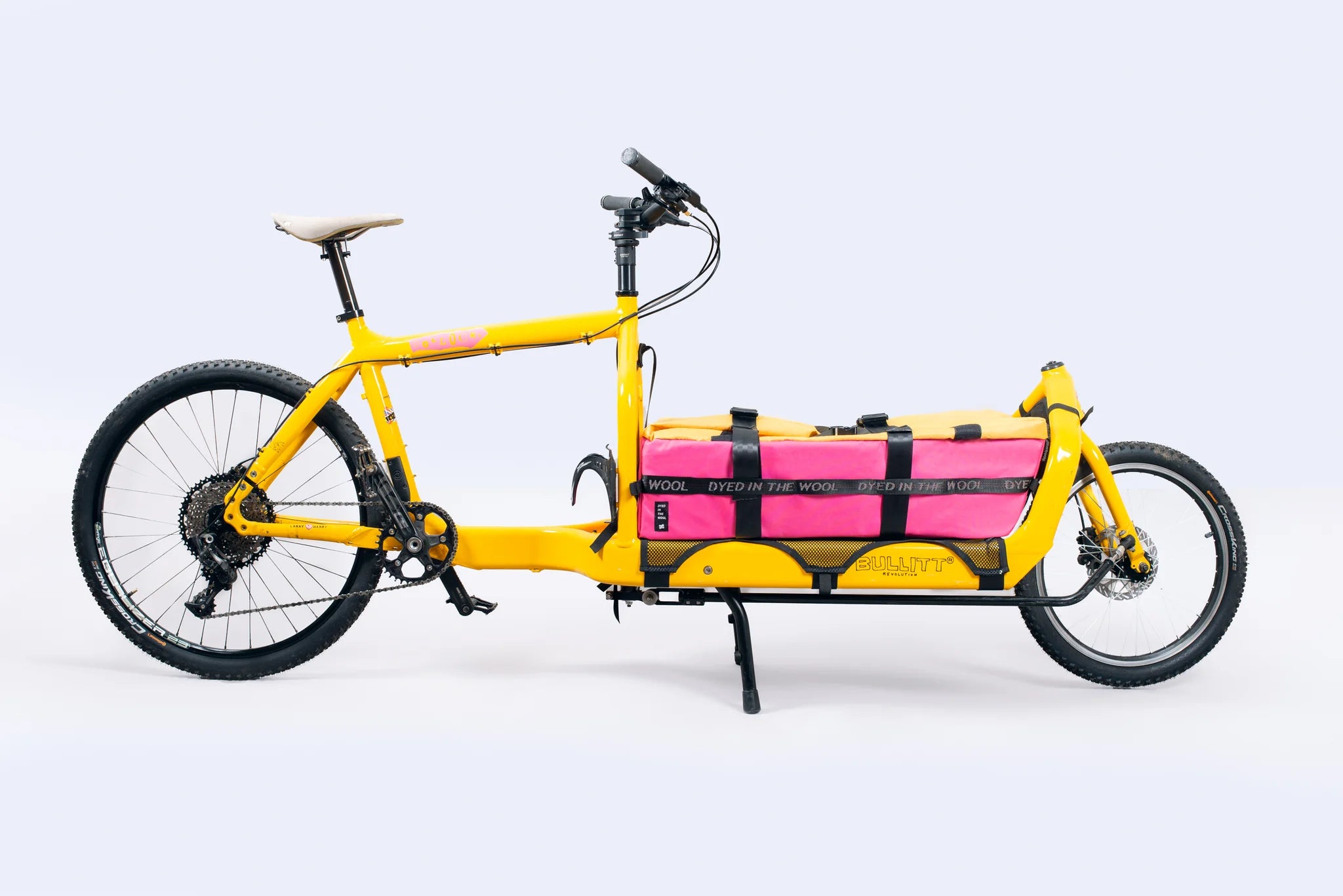 Yellow Bullitt cargo bike with pink and yellow storage bag on a white background