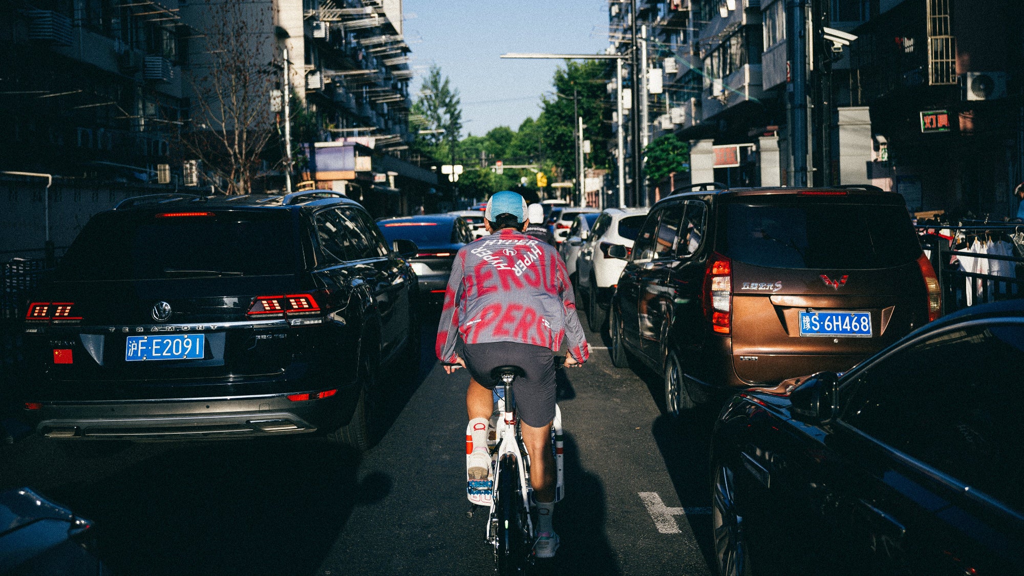A guy on a Bullitt cargo bike, seen from behind, riding in a congested city street.