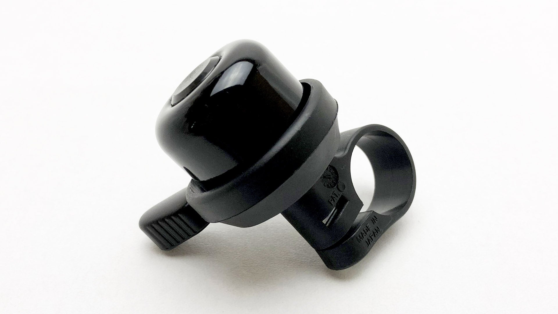A black bike bell lying on a white surface