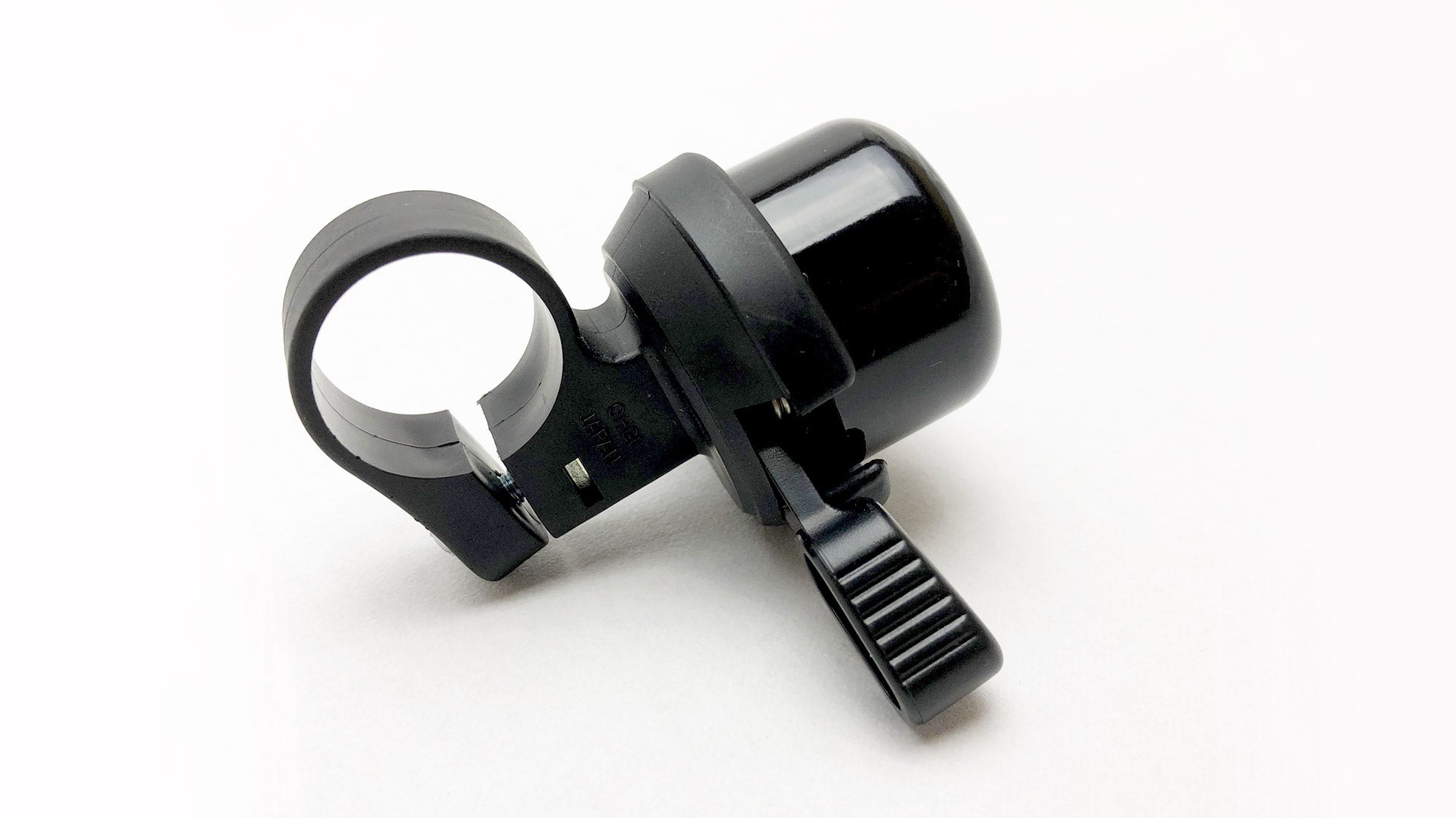 A black bike bell lying on a white surface