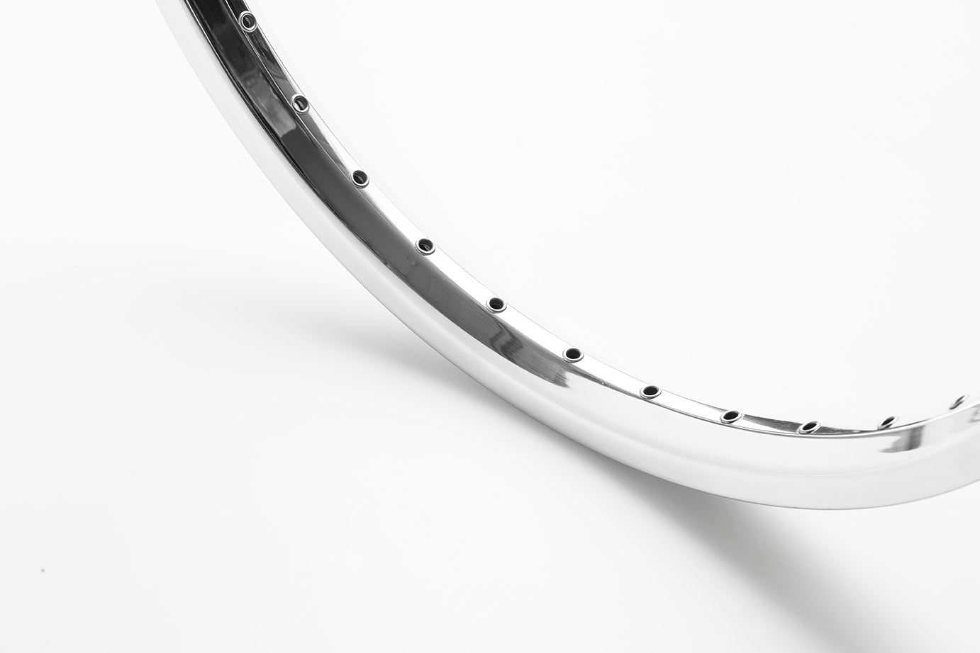 Closeup of a polished silver rim 26" standing on a white surface