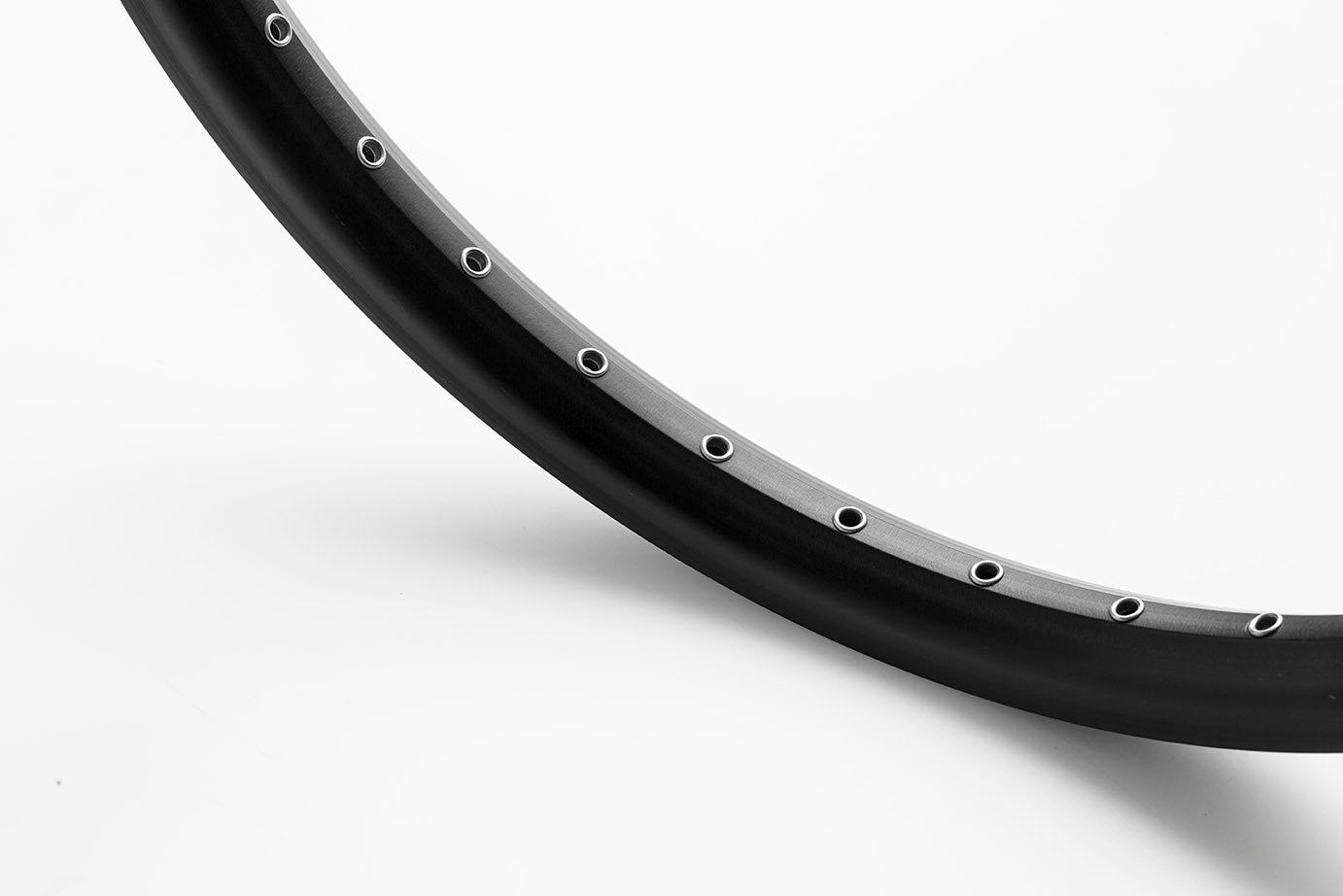 Closeup of a black rim 20" standing on a white surface