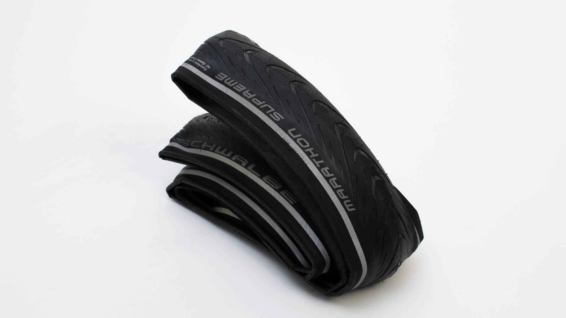 A Schwalbe Marathon Supreme folded tyre lying on a white surface