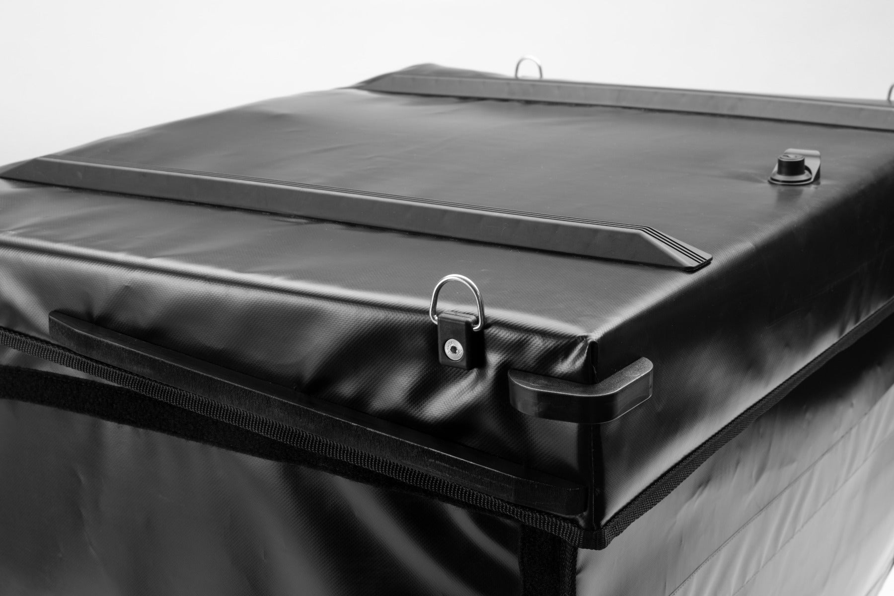 Black BagPRO box for Bullitt cargo bikes, with the lid closed. On the top of the lid you can see anchoring points for attaching extra cargo and plastic bumpers to protect the lid and the integrated lock.