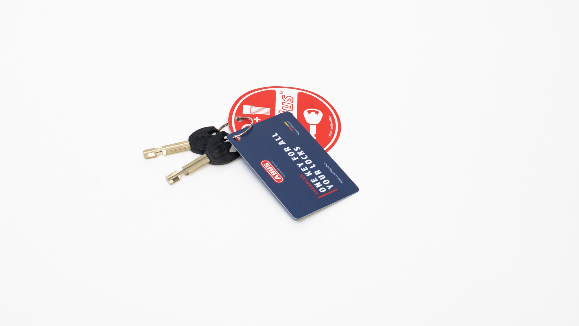 A set of ABUS bike lock keys on a white surface. A card is attached to the keyring, it reads: One key for all your locks, abus.com/yourplus