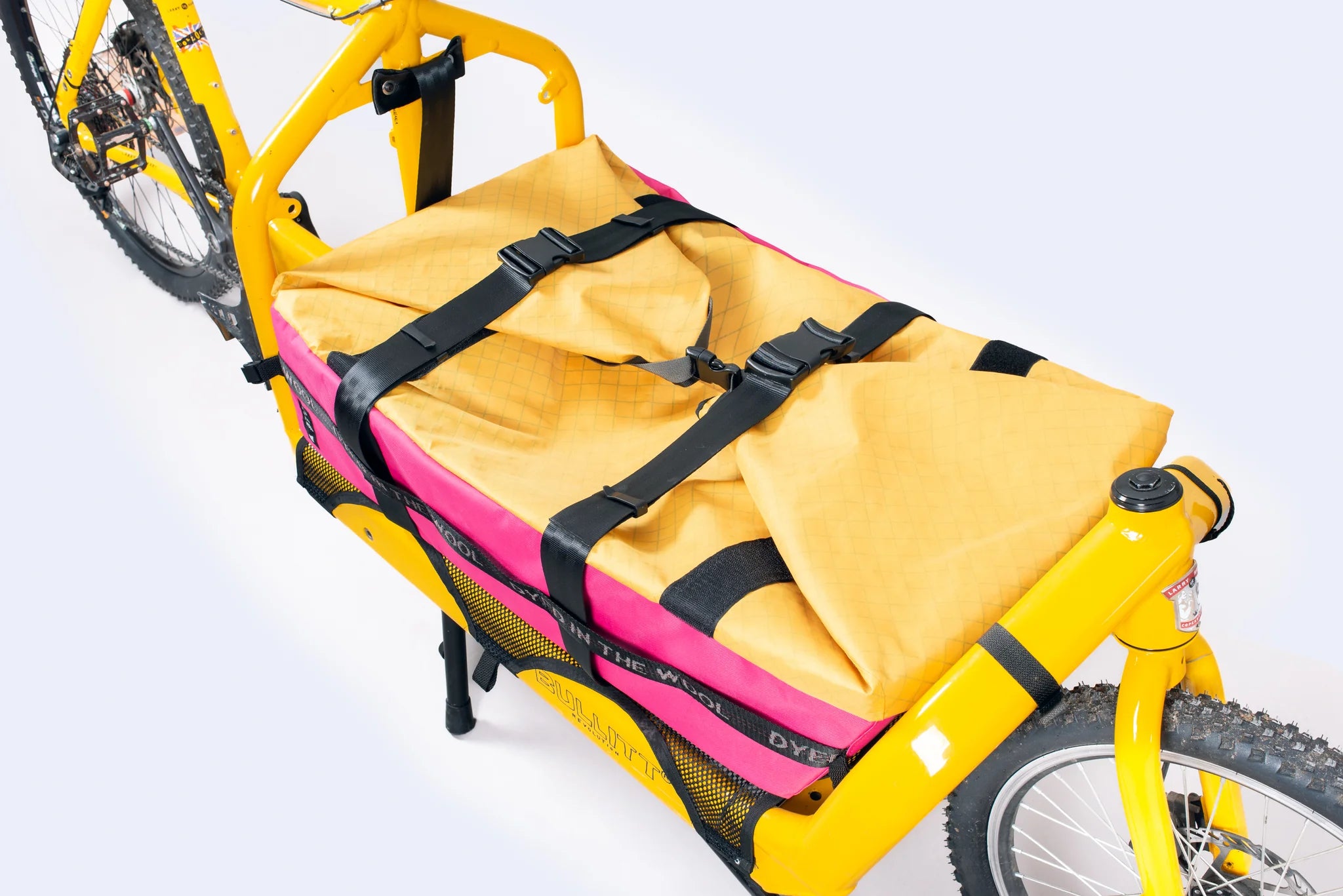Yellow Bullitt cargo bike with a pink and yellow bag on a white background