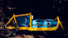 Yellow Bullitt cargo bike with blue and black bags parked in a forest