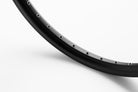 Closeup of a black rim 26" standing on a white surface